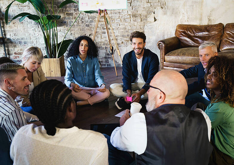 A multiracial creative marketing team of young people and adults sitting on the floor gathered together for business brainstorming