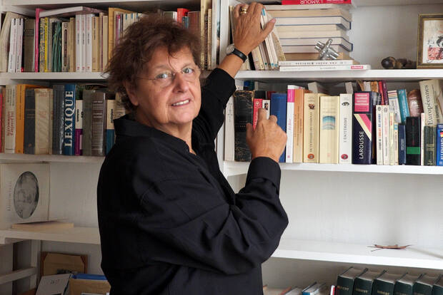 Femme souriante aux cheveux courts devant sa bibliothèque